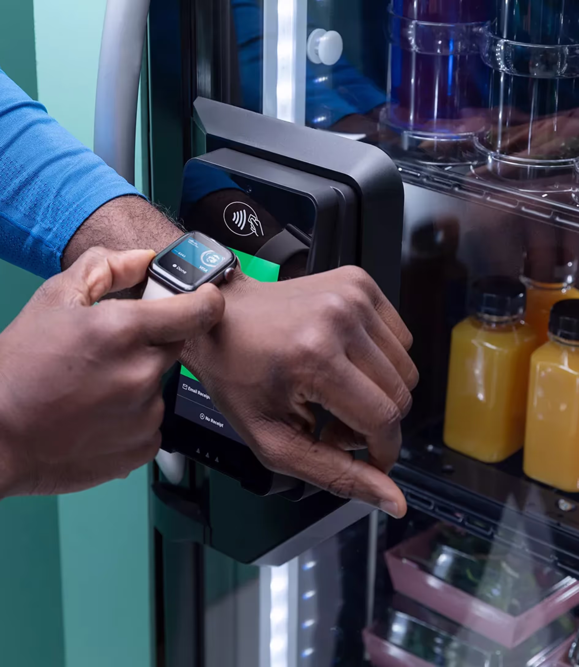 A customer paying at a smart cooler with a contactless watch tap.